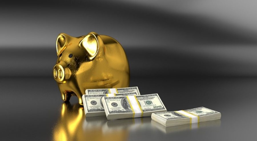 Image of money stacked next to a gold piggy bank to symbolize the money saved using a DSCR loan.