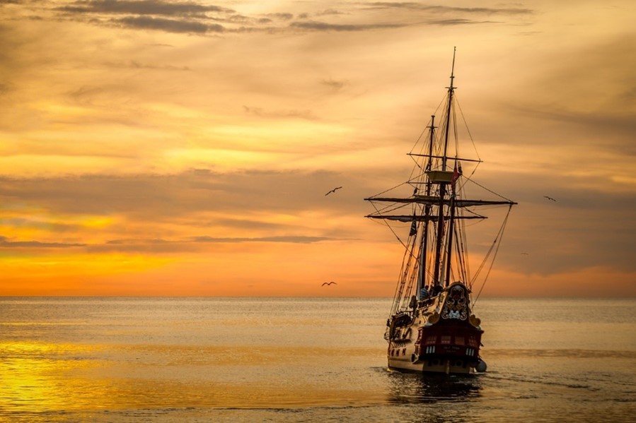 Image of a sailboat navigating out in the ocean after a storm.